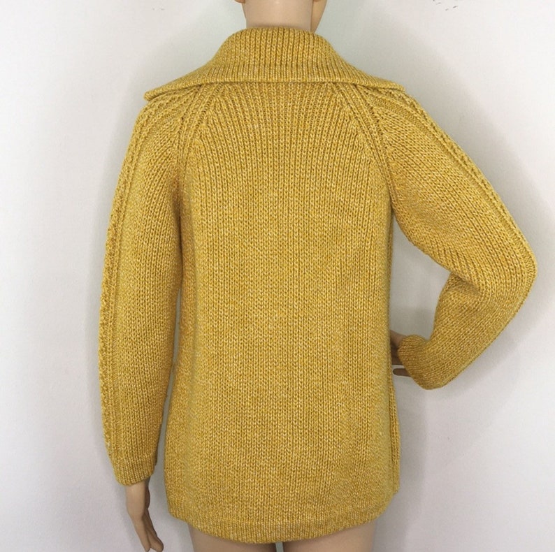 May include: A yellow knitted cardigan with a high collar and long sleeves.