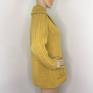 May include: A long-sleeved, yellow cardigan with a cable knit pattern and a collar. The cardigan has a relaxed fit and is made of a soft, comfortable material.