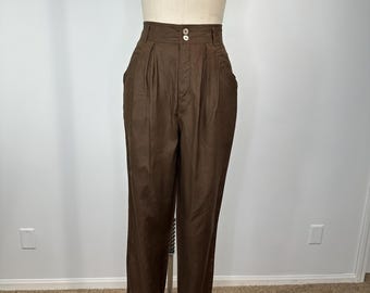 May include: Brown high-waisted trousers with a pleated front and two button closure. The pants are displayed on a mannequin. The trousers have two front pockets and a straight leg design. The fabric appears to be a medium-weight material.