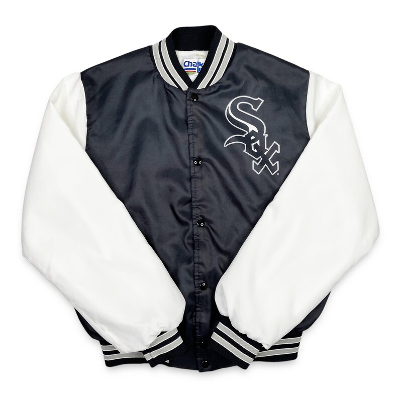May include: A black and white satin baseball jacket with white sleeves. The jacket features a black body with a white logo on the chest and a black collar with white and gray stripes. The sleeves are white, and the cuffs and hem have black and gray stripes.