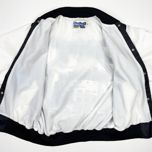May include: White and black vintage jacket with a snap front closure. The jacket has a black collar and trim, and a printed interior lining. The Chalk Line brand label is visible at the neck. The jacket is open, showing the interior lining.