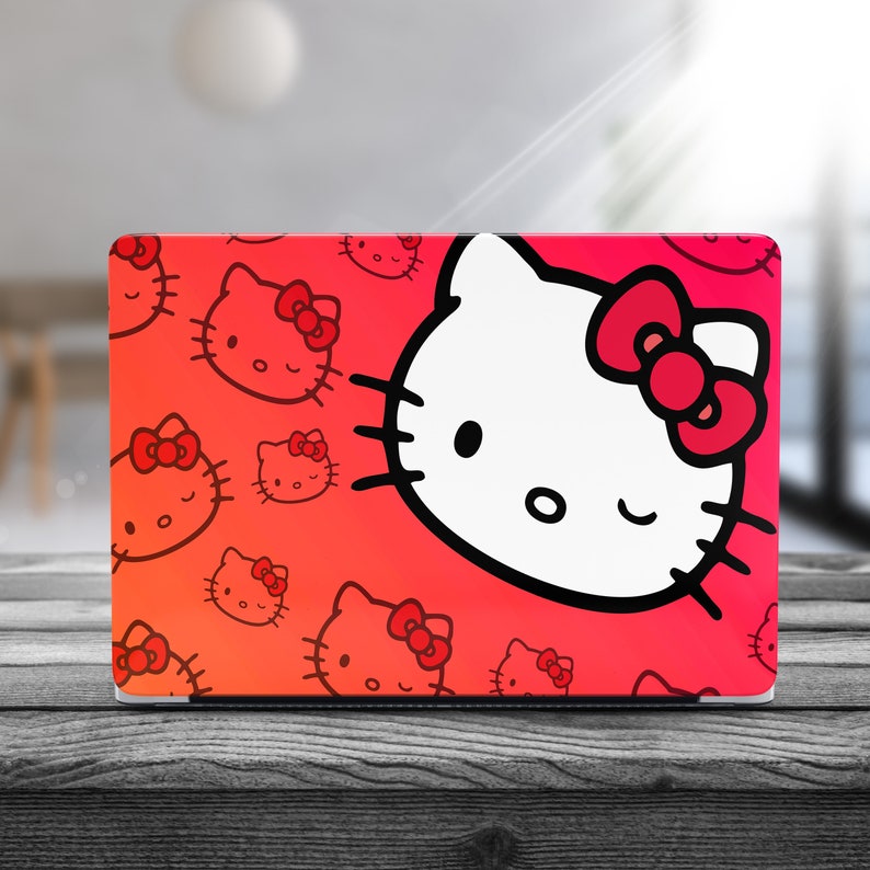 Peut inclure: Une peau d'ordinateur portable rouge avec un motif Hello Kitty blanc. Le motif repr&eacute;sente Hello Kitty avec un n&oelig;ud rouge et un clin d'&oelig;il. L'arri&egrave;re-plan est un d&eacute;grad&eacute; de rouge et de rose avec de plus petits visages d'Hello Kitty.