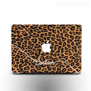 May include: A laptop computer with a leopard print skin. The Apple logo is visible on the lid. The text "Custom" is written in white cursive on the skin.