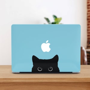 Può includere: Un laptop blu con un logo Apple bianco e una silhouette di gatto nero che spunta da dietro lo schermo.