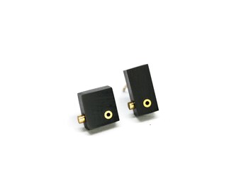 Mismatched black acrylic stud earrings with brass details