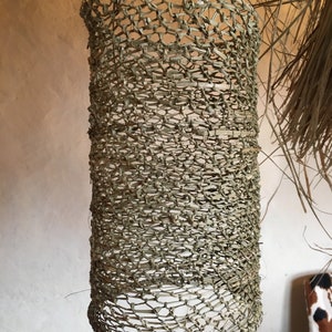 May include: A woven cylindrical lampshade made of natural materials, hanging from the ceiling.