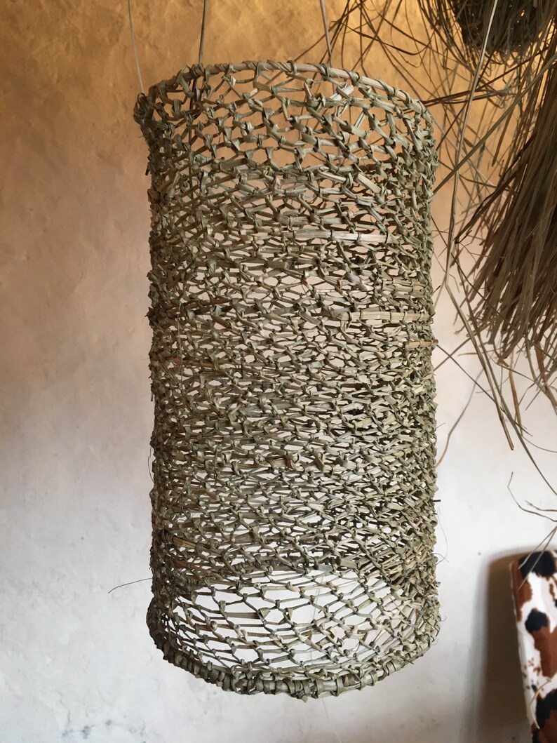 May include: A woven cylindrical lampshade made of natural materials, hanging from the ceiling.