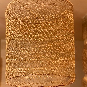 May include: A woven lampshade made of natural materials, with a light brown color and a delicate, intricate pattern.