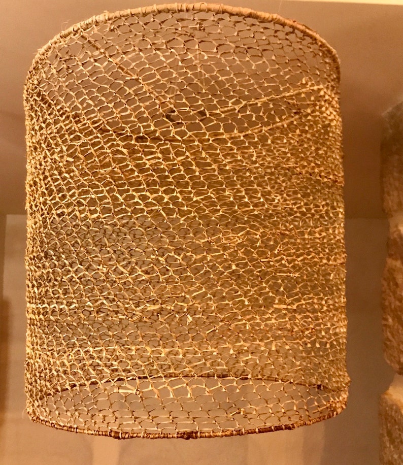 May include: A woven lampshade made of natural materials, with a light brown color and a delicate, intricate pattern.