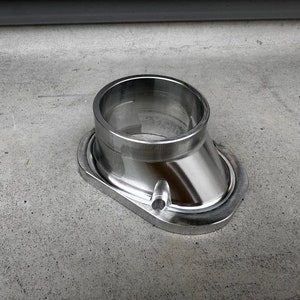 Puede incluir: Un accesorio de tubería de metal plateado con una abertura redonda y una base acampanada.