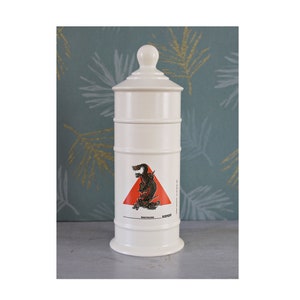 Peut inclure: Pot en céramique blanche avec un triangle rouge et un motif de dragon noir. Le pot a un couvercle et est étiqueté "sanofi" et "bermouloud".