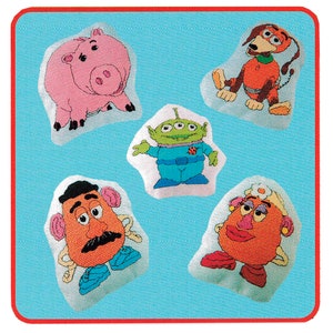 May include: Five plush toys from the Toy Story franchise. The toys are on a blue background. The toys are: a pink pig, a green alien, a brown potato head, a red potato head, and an orange dog.
