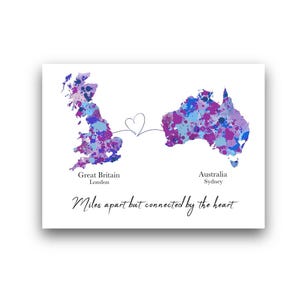 Può includere: Una stampa rettangolare con mappe ad acquerello della Gran Bretagna e dell'Australia in tonalità blu e viola. Una linea sottile collega le due masse terrestri con un cuore al centro. Il testo recita: Great Britain London, Australia Sydney e Miles apart but connected by the heart.