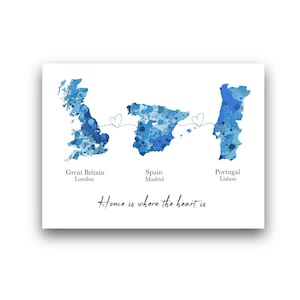 Può includere: Stampa bianca con mappe ad acquerello blu di Gran Bretagna, Spagna e Portogallo, collegate da cuori. Il testo include le città di Londra, Madrid e Lisbona, e la frase "Home is where the heart is."