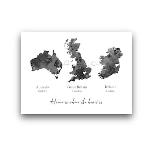 Op de afbeelding: Een zwart-wit print met aquarelkaarten van Australië, Groot-Brittannië en Ierland, verbonden door harten. De tekst bevat de locaties van Sydney, Londen en Dublin, met de zin "Home is where the heart is."