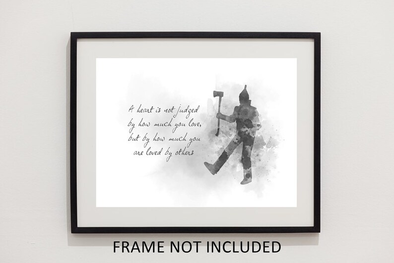 K&ouml;nnte beinhalten: Ein schwarz-wei&szlig;es Kunstdruck-Bild im Aquarellstil mit der Silhouette einer Blechfigur, die eine Axt h&auml;lt. Der Text lautet: A heart is not judged by how much you love, but by how much you are loved by others. Das Bild ist in einem schwarzen Rahmen.