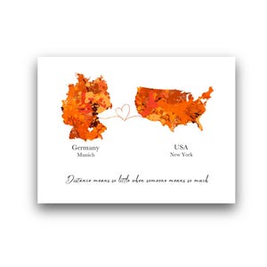 May include: A white print featuring orange and red watercolor maps of Germany and the USA, connected by a heart. Text reads "Germany Munich" and "USA New York." The quote "Distance means so little when someone means so much" is also included.