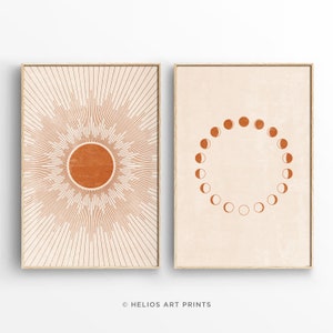 May include: A set of two minimalist art prints featuring a sun and moon design. The sun is depicted as a circle with radiating lines, while the moon is shown in various phases arranged in a circle. Both prints are in shades of orange and brown on a cream background.