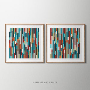 May include: Two framed abstract art prints with a geometric pattern of vertical stripes in shades of teal, orange, red, brown, and gray. The prints are in wooden frames.