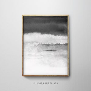 May include: Black and white abstract watercolor painting in a wooden frame. The painting features shades of gray and white, creating a layered effect. The artwork is framed with a thin, natural wood frame.