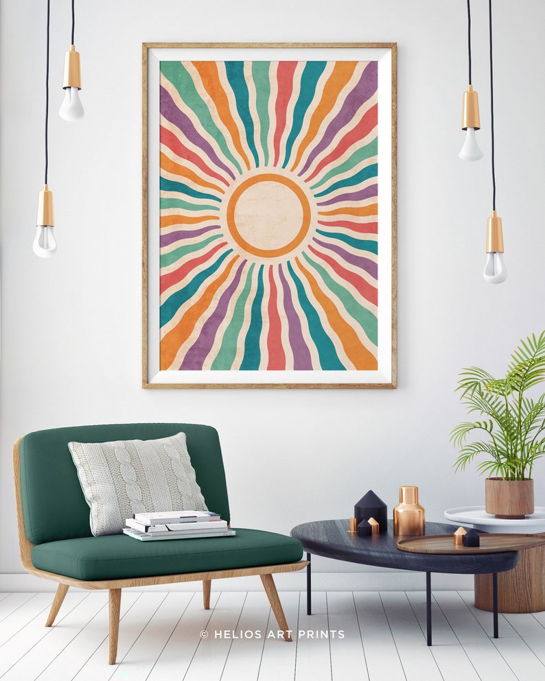 May include: A framed print of a colorful sunburst design with a white circle in the center. The sunburst is made up of wavy lines in shades of orange, red, purple, green, and blue. The print is hanging on a white wall in a living room setting.