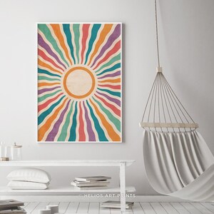 May include: A colorful abstract sunburst print with a white background and a circle in the center. The sunburst is made up of wavy lines in shades of orange, red, purple, teal, and green. The print is framed in a white frame. The text "HELIOS ART PRINTS" is at the bottom of the print.