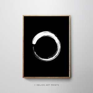 May include: A black and white minimalist art print featuring a white circle drawn with a brushstroke on a black background. The circle is incomplete, creating a sense of movement and flow. The print is framed in a simple wooden frame.