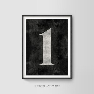 Puede incluir: Una impresión de arte imprimible en blanco y negro con el número uno en una fuente blanca audaz sobre un fondo negro con una textura desgastada.