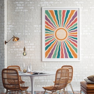 May include: A framed print with a retro sunburst design featuring colorful stripes in shades of orange, red, teal, purple, and yellow. The sunburst design is centered on a white circle with a textured background.