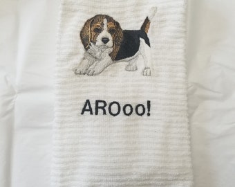 May include: White kitchen towel with an embroidered image of a beagle puppy and the text "AROOO!"
