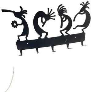 May include: Black metal key holder with four hooks shaped like stylized dancers. The key holder is mounted on a black metal bar.