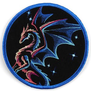 May include: A blue and pink embroidered dragon patch with a black background and silver glitter stars. The patch is circular with a blue border.