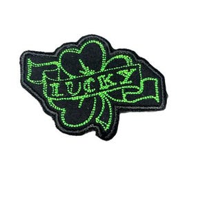 Puede incluir: Parche bordado negro y verde con un trébol de cuatro hojas y la palabra "LUCKY" en una pancarta.