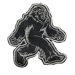 Op de afbeelding: Zwart-witte geborduurde patch van een Bigfoot die loopt. De patch is wit omrand en heeft een gedetailleerd ontwerp.