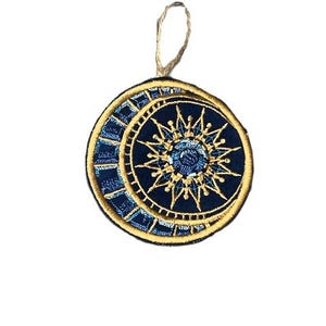 Op de afbeelding: Een blauwe en gouden geborduurde patch met een halve maan en een zon met een stervormig ontwerp.