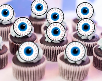 May include: A dozen cupcakes decorated with edible eyeball toppers. The cupcakes are frosted with a dark chocolate frosting and have a white rim around the base. The eyeballs are white with red veins and blue pupils.