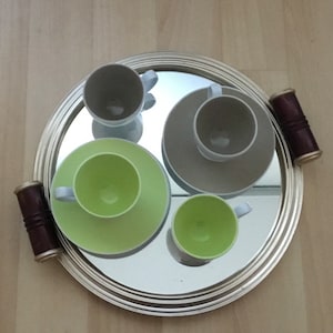 Peut inclure: Un plateau de service argenté avec une surface miroir et quatre tasses. Deux des tasses sont blanches avec un bord bleu clair, une est verte et une est blanche avec un bord bleu clair et une soucoupe verte.