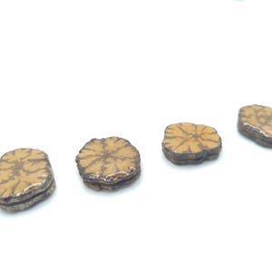 Può includere: Quattro bottoni in ceramica a forma di fiore di colore marrone e beige con un design in rilievo.