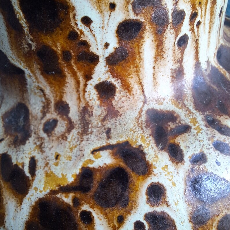 May include: Close-up of a ceramic vase with a white and brown mottled glaze. The glaze has a unique pattern of brown and white swirls and spots.