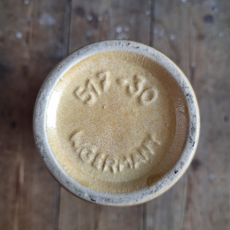 May include: A yellow ceramic vase with a brown rim and the text "517-30 GERMANY" on the bottom.