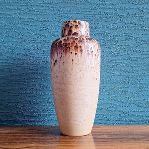 May include: A ceramic vase with a brown and white speckled glaze. The vase has a rounded body and a narrow opening.
