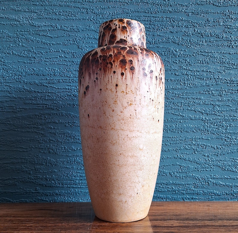 May include: A ceramic vase with a brown and white speckled glaze. The vase has a rounded body and a narrow neck.