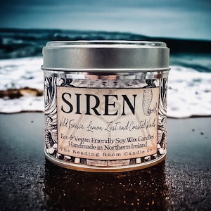 Può includere: Una candela in una lattina argentata con un'etichetta in bianco e nero che dice "SIREN Wild Freesia, Lemon Zest and Coastal Winds Eco & Vegan Friendly Soy Wax Candles Handmade in Northern Ireland The Reading Room Candle Co."