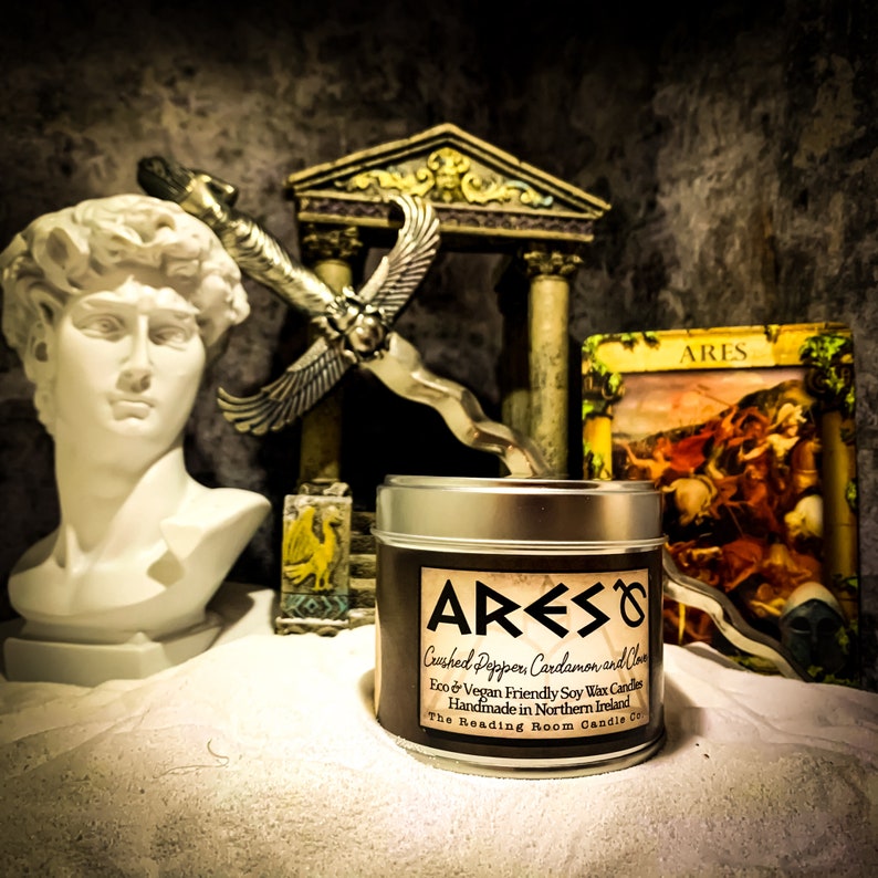 Puede incluir: Una lata de vela plateada con una etiqueta negra que dice "ARES Crushed Pepper Cardamon and clove Eco & Vegan Friendly Soy Wax Candles Handmade in Northern Ireland The Reading Room Candle Co."