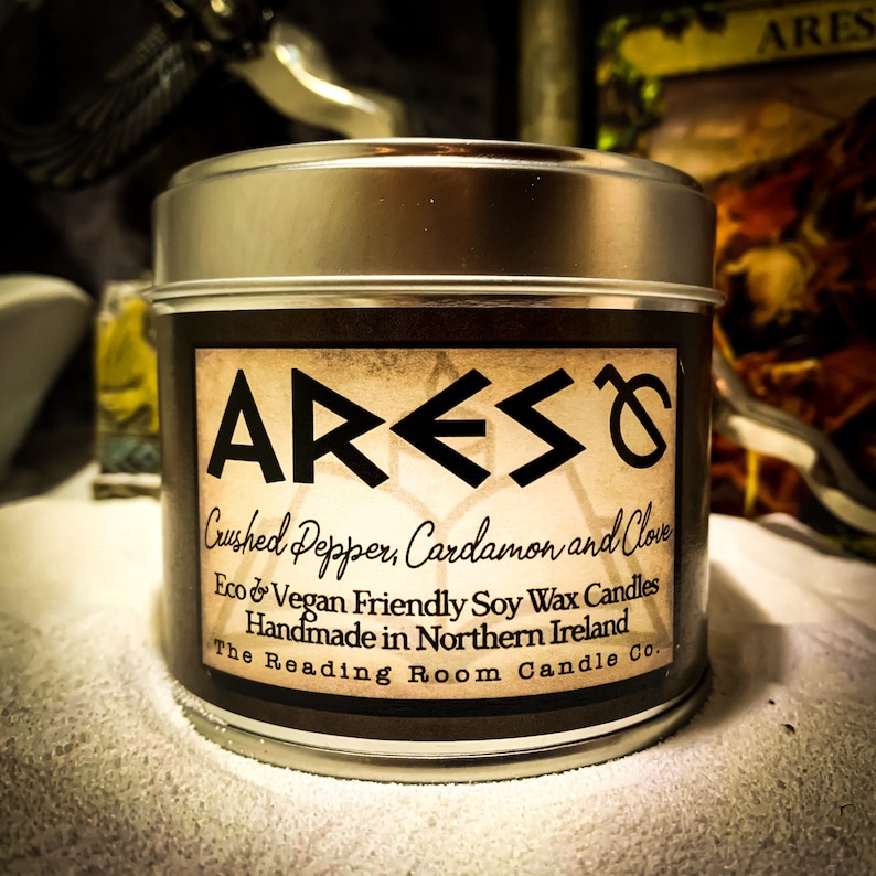 Puede incluir: Una vela en una lata de plata con una etiqueta marr&oacute;n que dice "ARES Crushed Pepper, Cardamon and Clove Eco & Vegan Friendly Soy Wax Candles Handmade in Northern Ireland The Reading Room Candle Co."