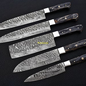 Puede incluir: Juego de cinco cuchillos de cocina de acero de Damasco con mangos de madera oscura. Las hojas tienen un dise&ntilde;o distintivo. Cada cuchillo tiene una virola plateada y remaches de lat&oacute;n. Dispuestos sobre una superficie negra.