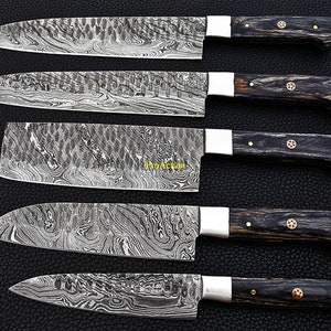 Puede incluir: Un surtido de cinco cuchillos de cocina de acero de Damasco. Las hojas tienen un dise&ntilde;o &uacute;nico y estampado. Cada cuchillo presenta un mango de madera oscura, virolas plateadas y remaches decorativos. Los cuchillos est&aacute;n dispuestos sobre una superficie oscura.