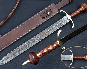 May include: A long, ornate sword with a patterned blade and a wooden handle. The sword features a gold-colored crossguard and pommel, and is accompanied by a brown leather sheath. The blade has a unique, textured pattern.