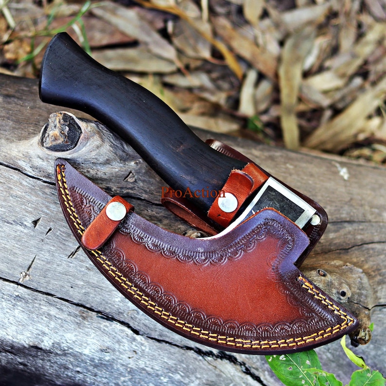 May include: A handcrafted knife with a dark wooden handle and a brown leather sheath. The sheath features decorative stitching and a button closure. The knife is partially sheathed, revealing a portion of the blade.