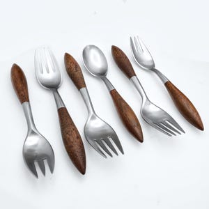 Puede incluir: Juego de seis utensilios de servicio plateados con mangos de madera. Los utensilios incluyen cucharas y tenedores.